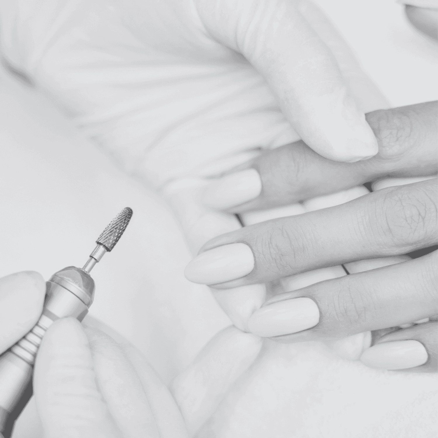 A person receiving a manicure with an electric nail file in a spa setting.