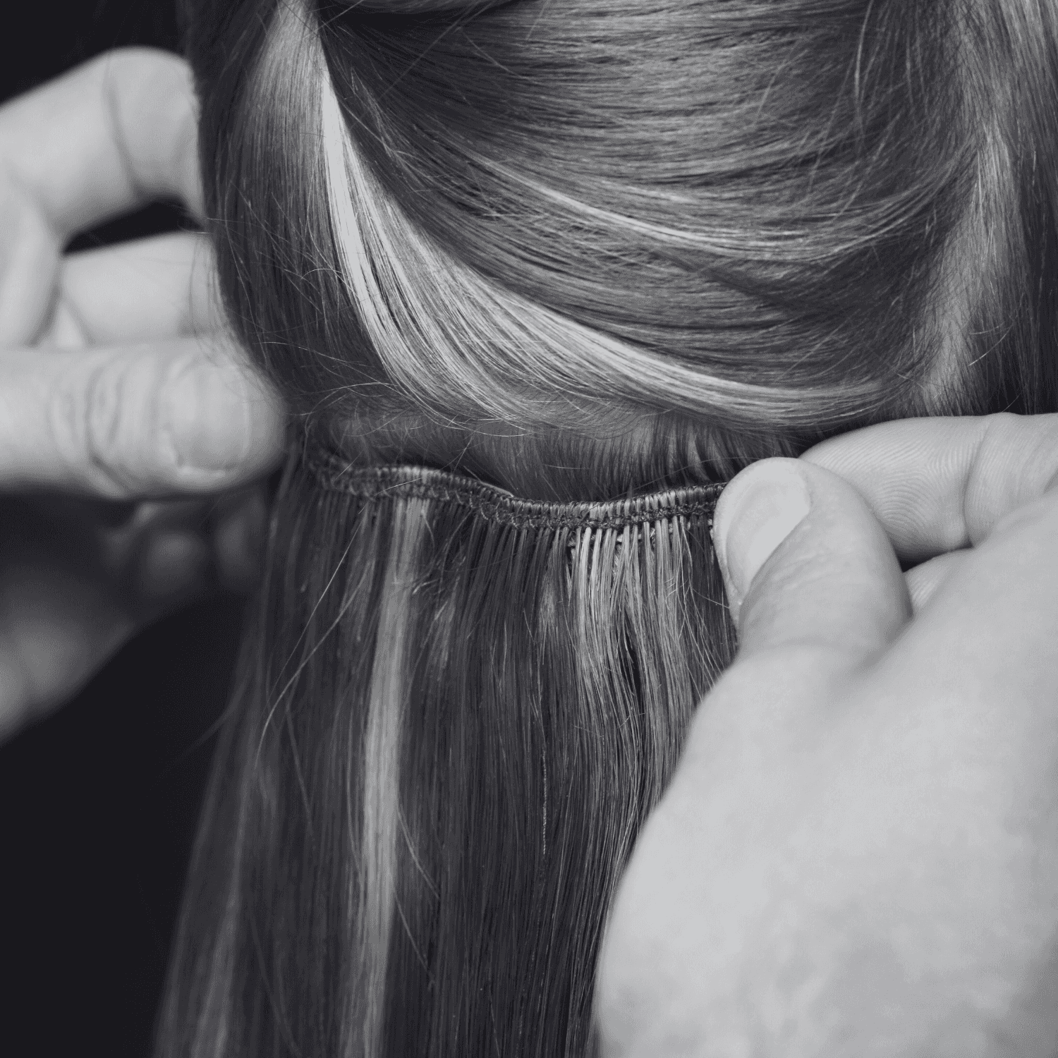 Hair extensions being carefully applied in a salon setting.