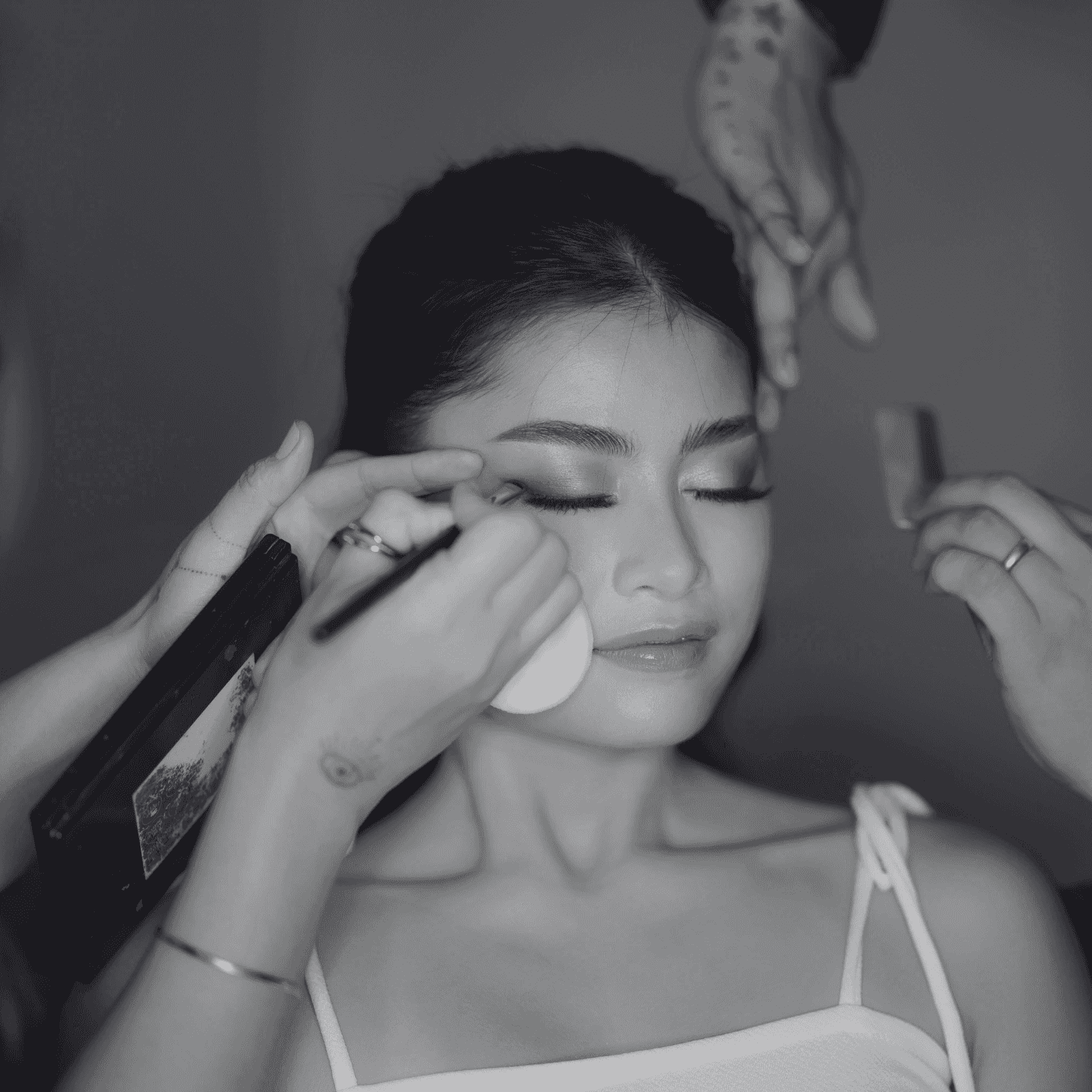 Makeup artist applying cosmetics to a woman’s face with brushes and sponges.